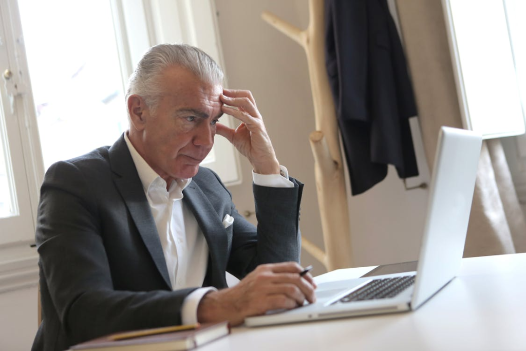 a man in a black blazer sitting at his desk
