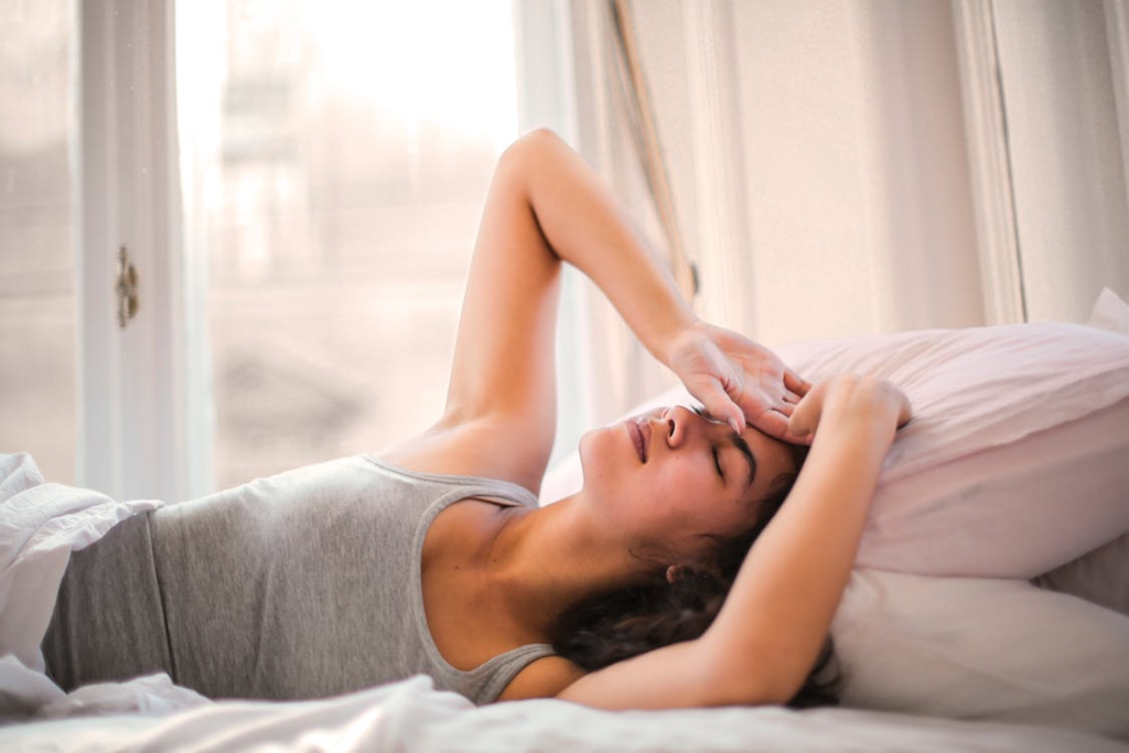 a woman lying in her bed in a gray tank top