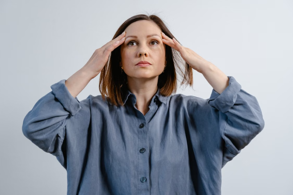 A-woman-holding-her-head-from-a-headache.webp